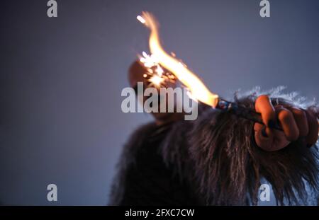 Mann, der vor grauem Hintergrund ein Feuerwerk hält Stockfoto