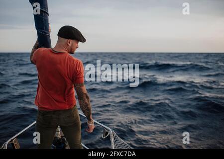 Mann, der am Rand des Bootes im Meer steht Stockfoto