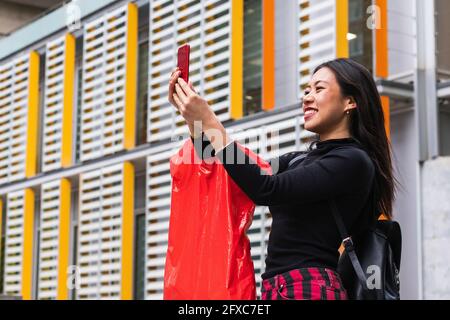 Frau lächelt, während sie Selfie über das Mobiltelefon nimmt Stockfoto
