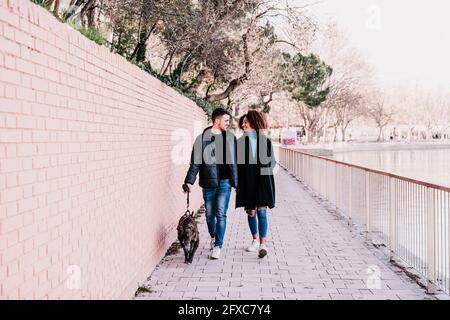 Junges Paar, das mit Hund auf dem Fußweg läuft Stockfoto