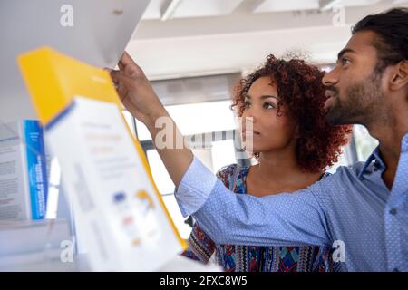 Internationale Unternehmer und Unternehmerinnen diskutieren in der Nähe des Bücherregals im Büro Stockfoto