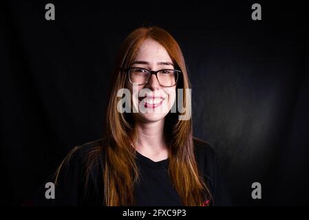 Lächelnde Frau mit Brille vor schwarzem Hintergrund Stockfoto
