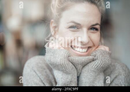 Frau mittleren Erwachsenen trägt Pullover lächelnd mit der Hand am Kinn Stockfoto