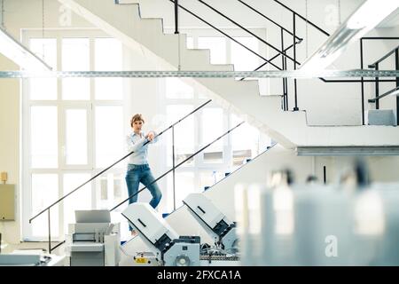 Reife Geschäftsfrau, die auf der Treppe in der Werkstatt steht Stockfoto