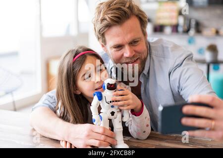Vater nimmt Selfie über Handy mit Tochter und Roboter Spielzeug zu Hause Stockfoto