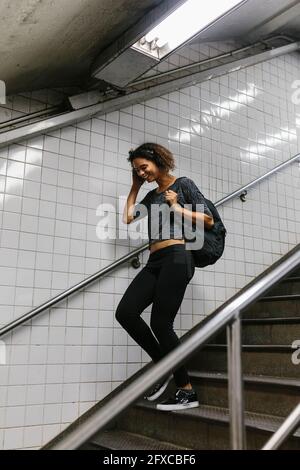 Junge Frau mit Kopf in der Hand, die in der U-Bahn über die Stufen läuft Stockfoto