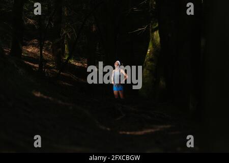 Lächelnde Frau, die im dunklen Wald steht Stockfoto