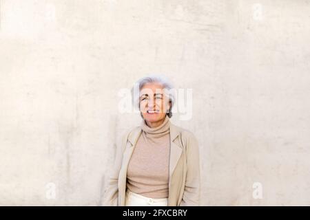 Lächelnde reife Frau vor der Wand Stockfoto