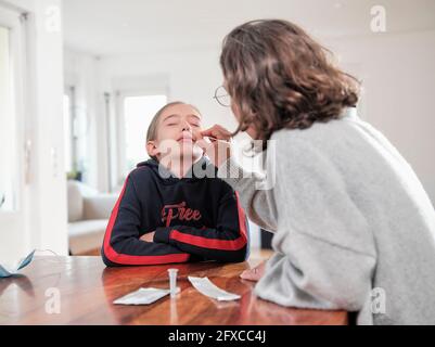 Reife Frau, die zu Hause den Covid-19-Test der Tochter macht Stockfoto