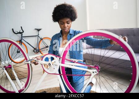 Afro Frisur Frau Reparatur Fahrrad zu Hause Stockfoto