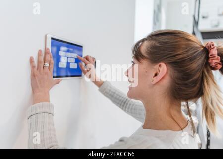 Lächelnde Frau, die das Bedienfeld zu Hause benutzt Stockfoto