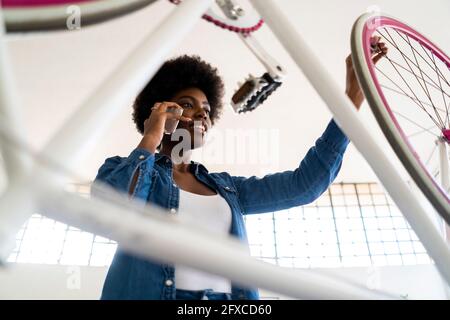 Afro-Frau, die während der Reparatur eines Fahrrads ein Mobiltelefon verwendet Stockfoto