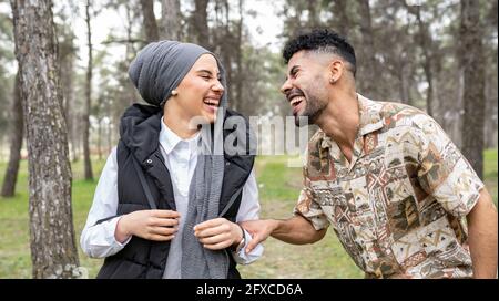 Junger Mann, der mit der Frau im Wald lacht Stockfoto