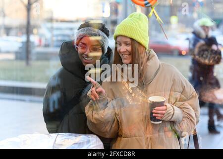 Weibliche Freunde in Strickmütze genießen Schaufensterbummel im Winter Stockfoto