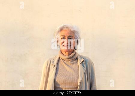 Reife Frau lächelt vor der Wand Stockfoto