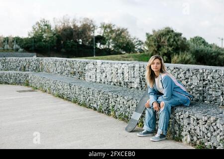 Frau, die auf einer Steinbank im Skateboard-Park sitzt Stockfoto