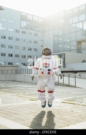 Weibliche Astronautin in der Luft in der Nähe des Gebäudes an sonnigen Tagen Stockfoto