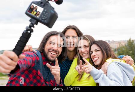 Glückliche Frau, die beim Vlogging in der Natur aus der Zunge ragt Stockfoto