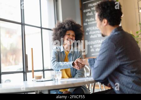 Männlicher Kunde, der nach einem Treffen im Café mit einer Geschäftsfrau Händeschütteln machte Stockfoto