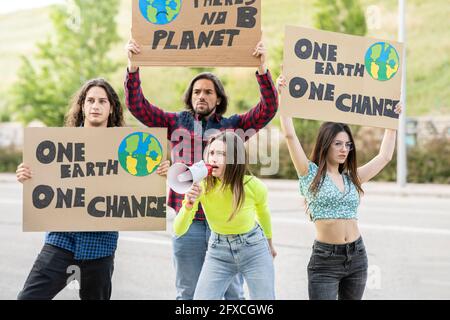 Junge Frauen mit Männern protestieren auf dem Weg zum Klimawandel Stockfoto