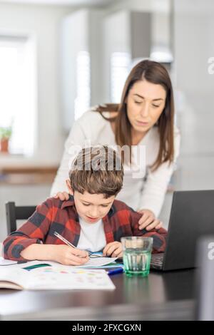 Mutter, die dem Sohn hilft, zu Hause zu studieren Stockfoto