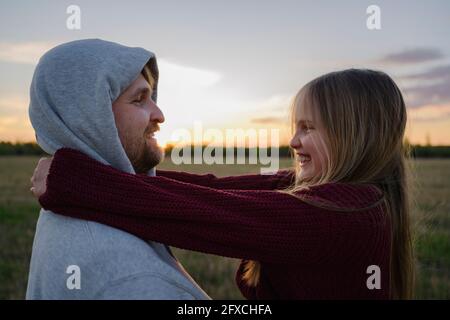 Glückliche Tochter, die den Vater während des Sonnenuntergangs ansah Stockfoto