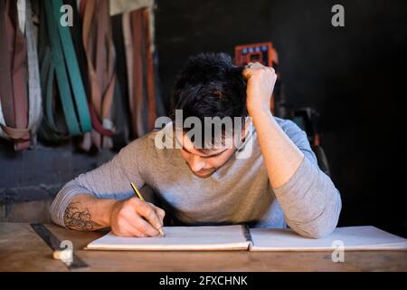 Handwerker beim Zeichnen auf Buch in der Werkstatt Stockfoto