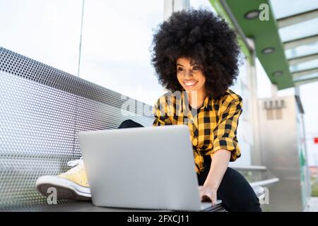 Frau mit Laptop auf Bank Stockfoto