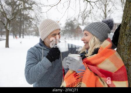 Lächelndes Seniorenpaar, das im Winter Tee in einem Becher trinkt Stockfoto