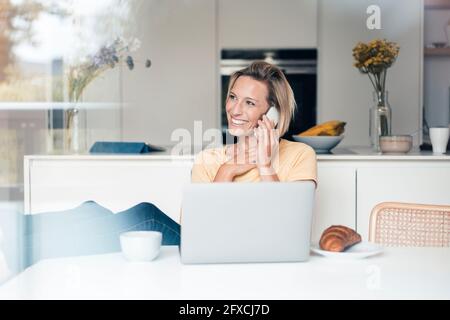 Lächelnde Unternehmerin im Gespräch mit dem Handy Stockfoto