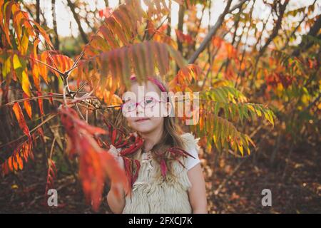 Nettes Mädchen tragen Brillen stehen bei Pflanzen im Herbst Stockfoto