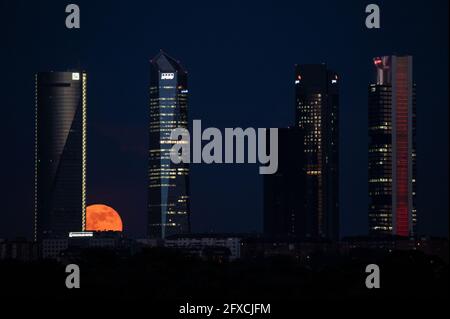 Madrid, Spanien. Mai 2021. Der Vollmond im Mai, der auch als Blumenmond bekannt ist, steigt über den Wolkenkratzern des Four Towers Business Area auf. In einigen Teilen der Welt wird ein seltener, simultaner Blutsübermond und eine Mondfinsternis auftreten. Quelle: Marcos del Mazo/Alamy Live News Stockfoto