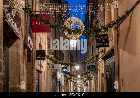 Traditionelle schmale Straße in einer alten europäischen Stadt bei Nacht mit Weihnachtsschmuck - Montpellier, Südfrankreich Stockfoto