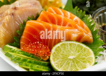Sashimi-Set, japanische Küche. Sushi-Restoran-Menü. Japanische Meeresfrüchte. Sashimi-Set auf Teller mit Gurke und Salat Stockfoto