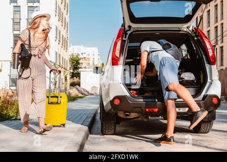 Paar sammeln für Road Trip. Putting Taschen auf Auto-Kofferraum. Sommerferien Stockfoto