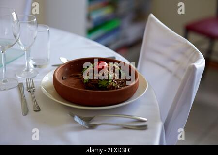 Buchweizen Soba Nudeln mit Kräutern und Tomaten in einem hölzernen Teller auf einem weißen Tisch Restaurant Stockfoto