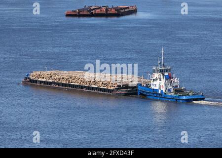 Im Sommer transportiert die Barge Fracht, Holzstämme entlang des Flusses. Stockfoto