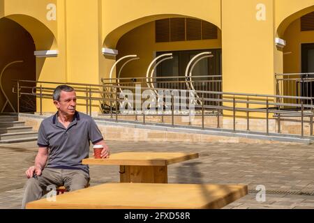 Ein erwachsener älterer Mann sitzt an einem Tisch und trinkt Kaffee Stockfoto