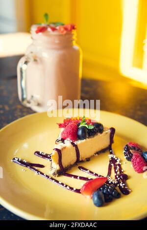 Smoothie und Käsekuchen mit gelbem Hintergrund. Konzept von gesund Stockfoto