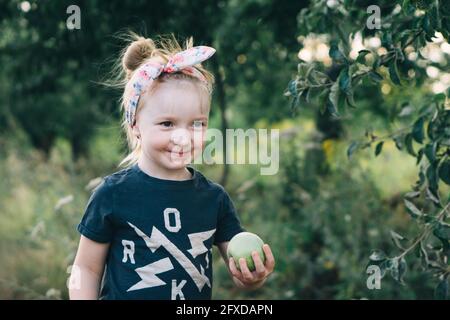 Nettes Mädchen hält einen grünen Apfel in den Händen Stockfoto