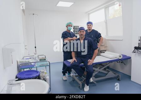 Multiethnischer orthopädischer Arzt vor seinem medizinischen Team sucht An der Kamera trägt Gesichtsmaske Stockfoto