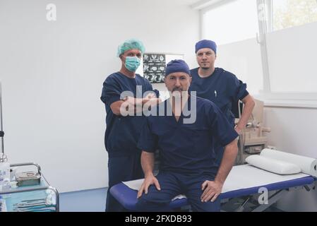 Multiethnischer orthopädischer Arzt vor seinem medizinischen Team sucht An der Kamera trägt Gesichtsmaske Stockfoto