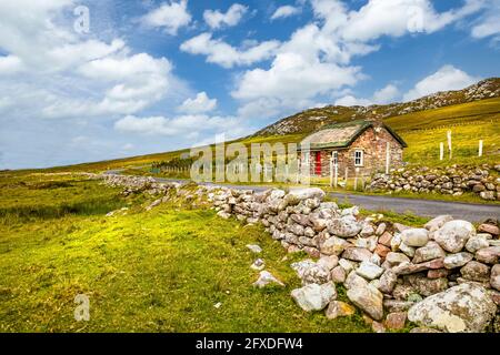 Traditionelles irisches Reethaus und Steinmauer oder Zaun an Achill Island in der Grafschaft Mayo Irland Stockfoto