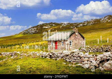 Traditionelles irisches Reethaus und Steinmauer oder Zaun an Achill Island in der Grafschaft Mayo Irland Stockfoto