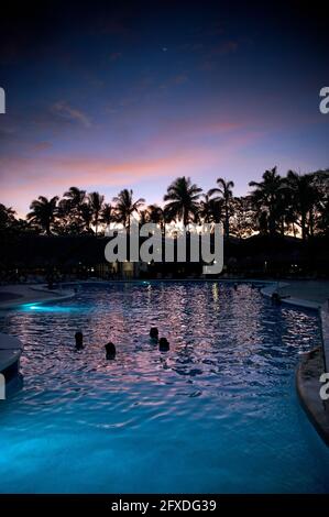 Menschen, die den Sonnenuntergang von einem Schwimmbad in einem Resort in Tamarindo, Costa Rica, Mittelamerika aus beobachten Stockfoto