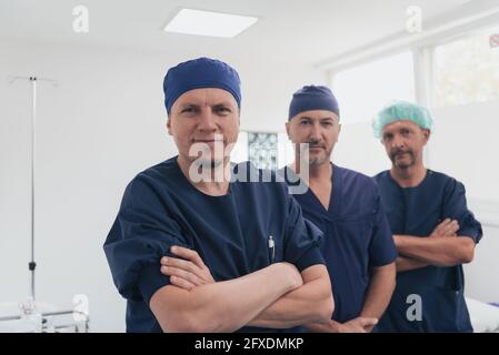 Multiethnischer orthopädischer Arzt vor seinem medizinischen Team sucht An der Kamera trägt Gesichtsmaske Stockfoto
