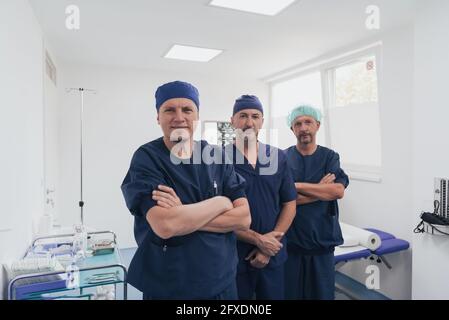 Multiethnischer orthopädischer Arzt vor seinem medizinischen Team sucht An der Kamera trägt Gesichtsmaske Stockfoto