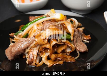 Rindfleisch in schwarzer Bohnensauce mit flachen Reisnudeln in einem koreanischen Restaurant. Stockfoto