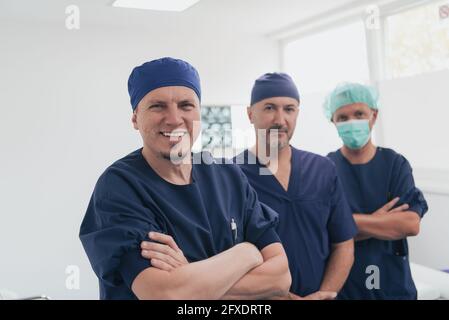 Multiethnischer orthopädischer Arzt vor seinem medizinischen Team sucht An der Kamera trägt Gesichtsmaske Stockfoto