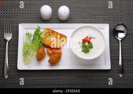 Creme der Pilzsuppe in einer weißen Schüssel mit angeordnet Geröstetes Brot und frischer grüner Gemüse-Salat als Beilage Auf einem weißen Servierbrett angeordnet Stockfoto